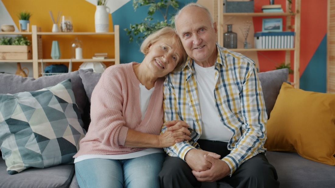 An older couple smiling together on a couch